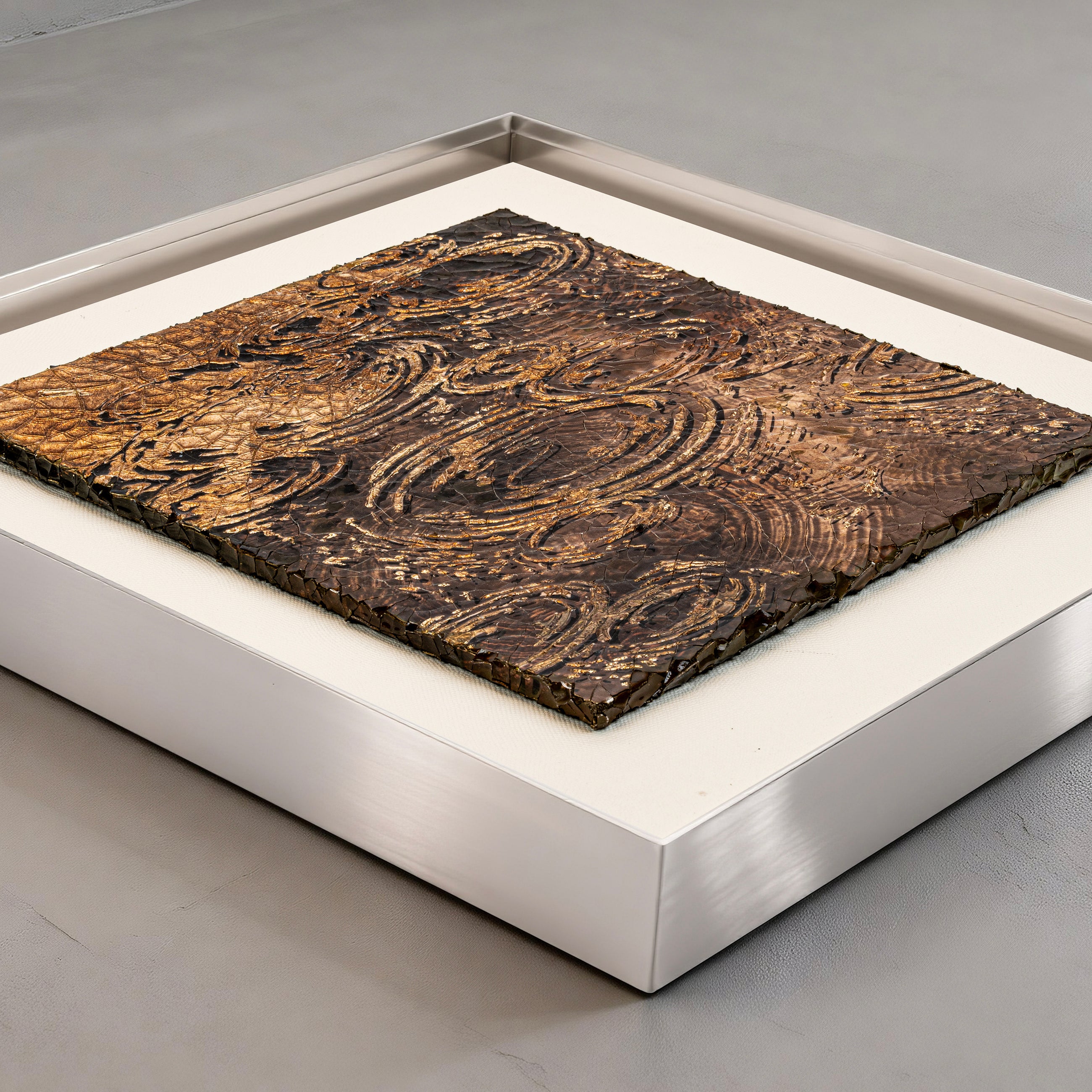 Flat-lay overhead view of Harvest Tide — Patinated Foil · Aura Frame, capturing the full expanse of its 3D water element mineral terrain as concentric wave ridges gather and spiral upward, the heat-graduated foil catching light across crackle texture throughout.