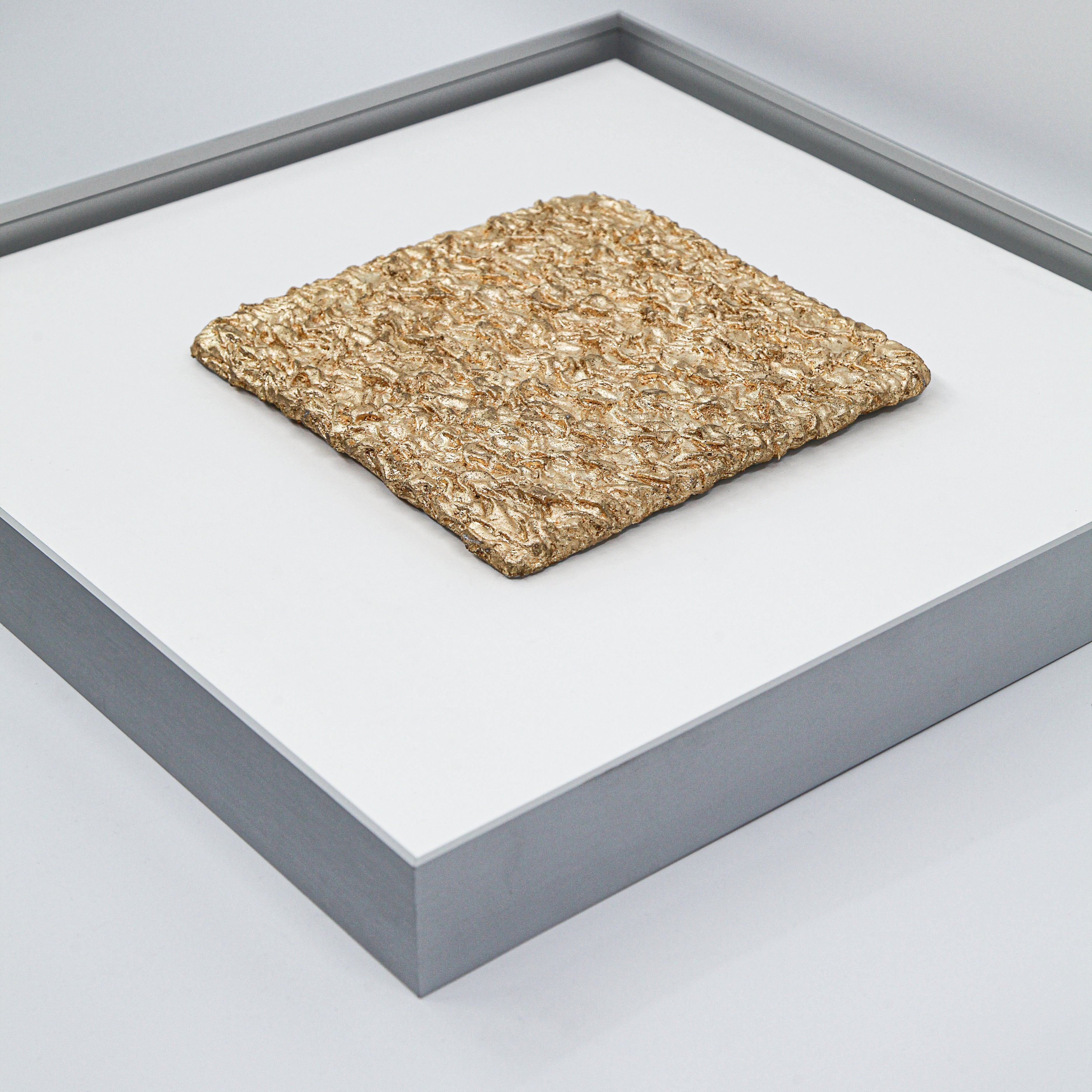 Flat-lay overhead view of Shan — Gilded Foil · Aura Frame, capturing the full expanse of its earth element mineral terrain — mountain ridgelines and cracked earth fissures folded by hand across the entire surface, gilded foil tracing every ridge as the visual grammar of wealth within the earth.