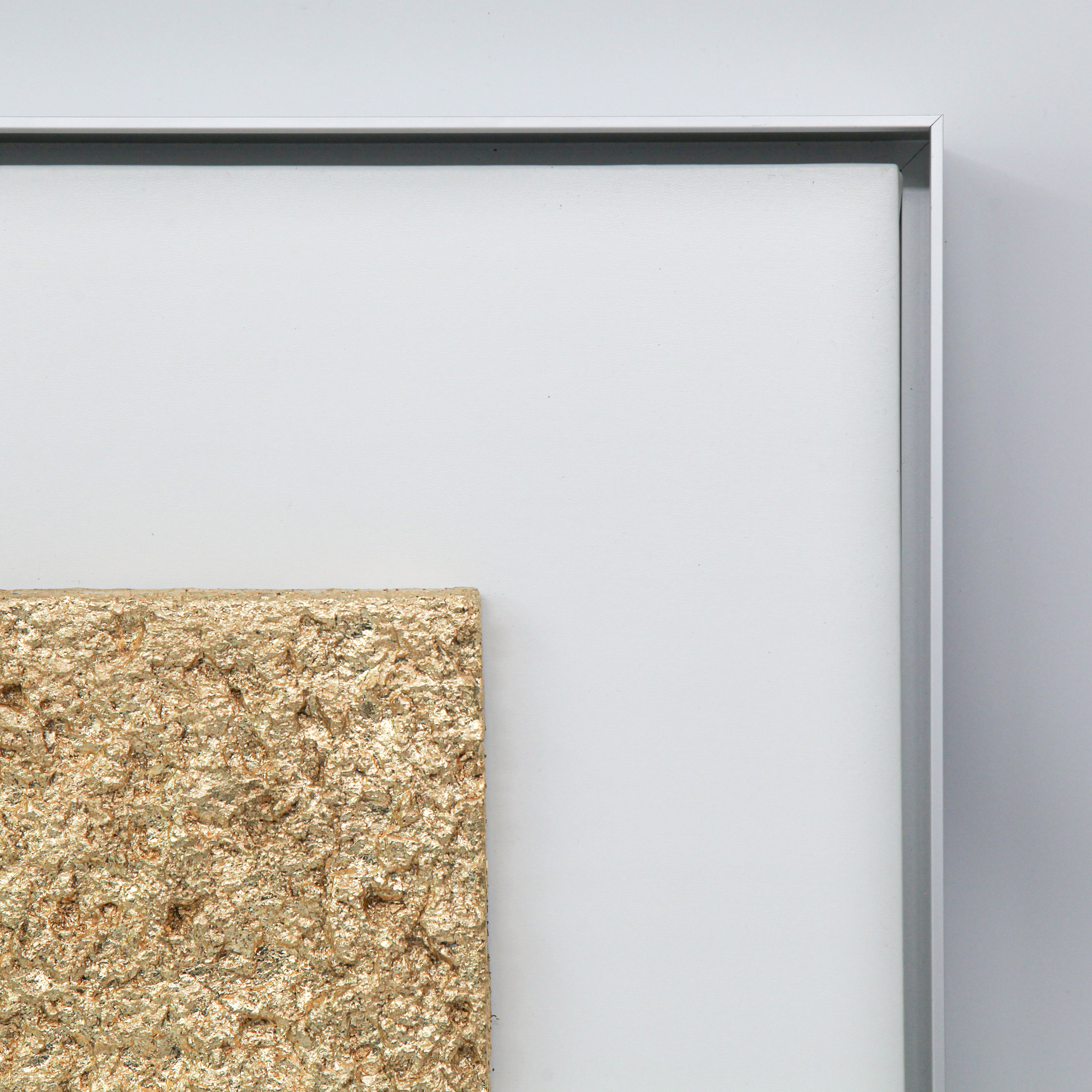 Corner detail of Solstice — Gilded Foil · Aura Frame, showing the hand-laid 0.1-micron gilded foil settling along the fire element mineral mountain relief — bright on the high ground, warm and receded in the valleys, the 3D textured surface alive with directional light.